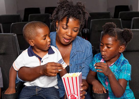 An African American family eating popcorn at a movie